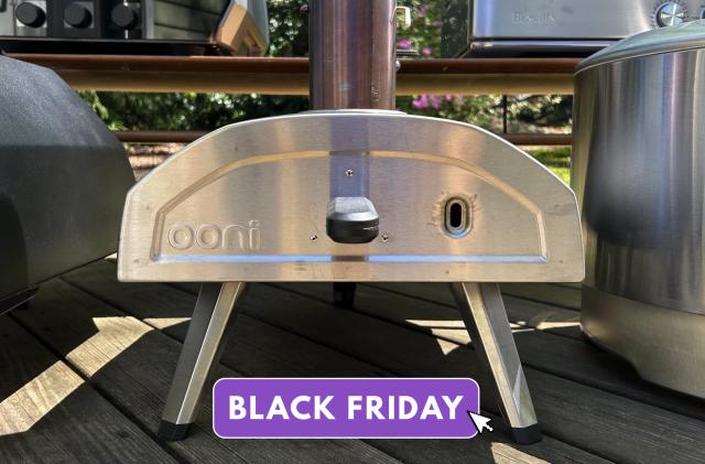 Outdoor photo of the Ooni Fyra 12 Wood Pellet Pizza Oven on a table next to other ovens. A purple overlay says "Black Friday."