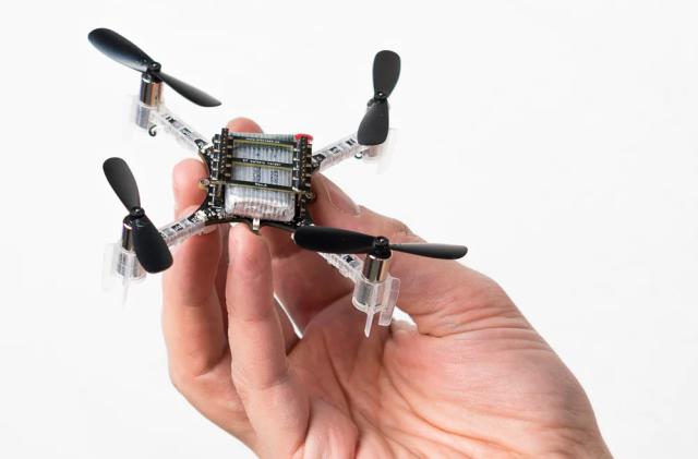 Photo of a hand holding a small quadcopter drone.