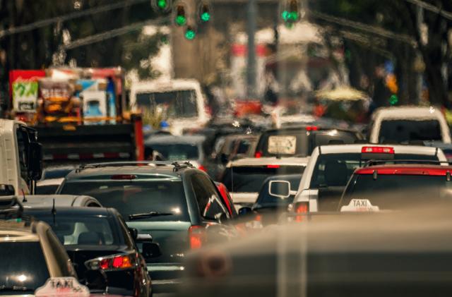 Heavy traffic and in the horizon the Metropolitan Cathedral in Mexico City, we can see cars, police trying to fix the traffic some street lights and far on the horizon, we can see the zocalo flag and the metropolitan cathedral. ​