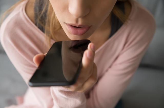 Close up girl sitting on couch hold on hand phone talk on speakerphone through microphone built into device loud reproduction of speech, voice recognition distant communication, translator app concept