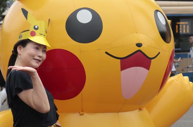 A woman poses with a balloon of Pokemon character Pikachu at Minatomirai shopping district in Yokohama, near Tokyo, Monday, Aug. 14, 2017. (AP Photo/Shizuo Kambayashi)