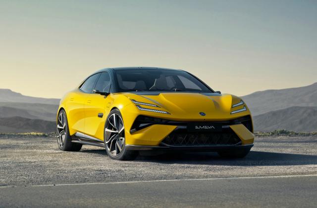 A Lotus Emeya EV in yellow is parked by the side of a desert road with low hills in the distance.