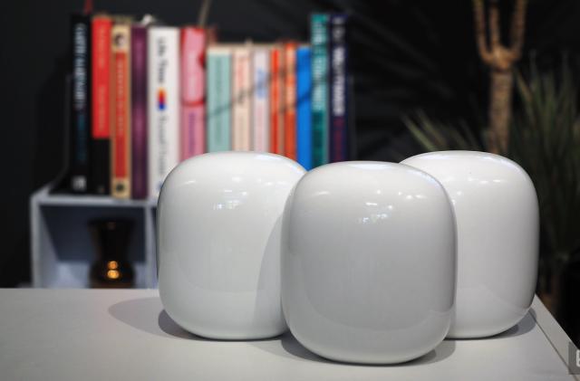 Image of three Nest WiFi Pro units on a table in front of a blurred bookshelf.