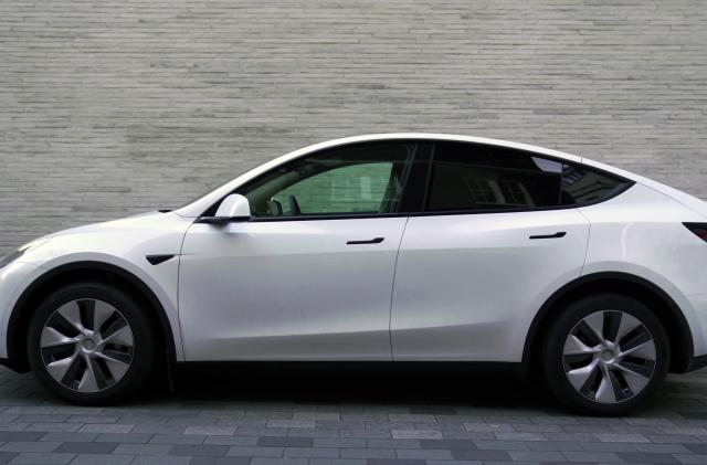 Kentucky, United States - February 27, 2022: Side view of a white Tesla Model Y, parked on the street, of a city. In the background a building.