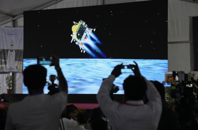 Journalists film the live telecast of spacecraft Chandrayaan-3 landing on the moon at ISRO's Telemetry, Tracking and Command Network facility in Bengaluru, India, Wednesday, Aug. 23, 2023. India lands a spacecraft near the moon’s south pole, becoming the fourth country to touch down on the lunar surface. (AP Photo/Aijaz Rahi)