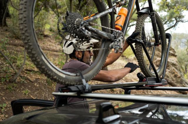 A photo of someone storing a mountain bike on top of a Rivian R1T truck. 