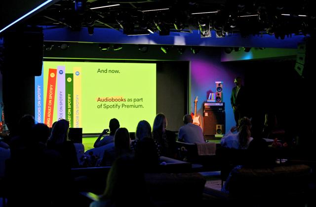 A dark stadium with a screen on stage announcing audiobooks as part of Spotify Premium.  